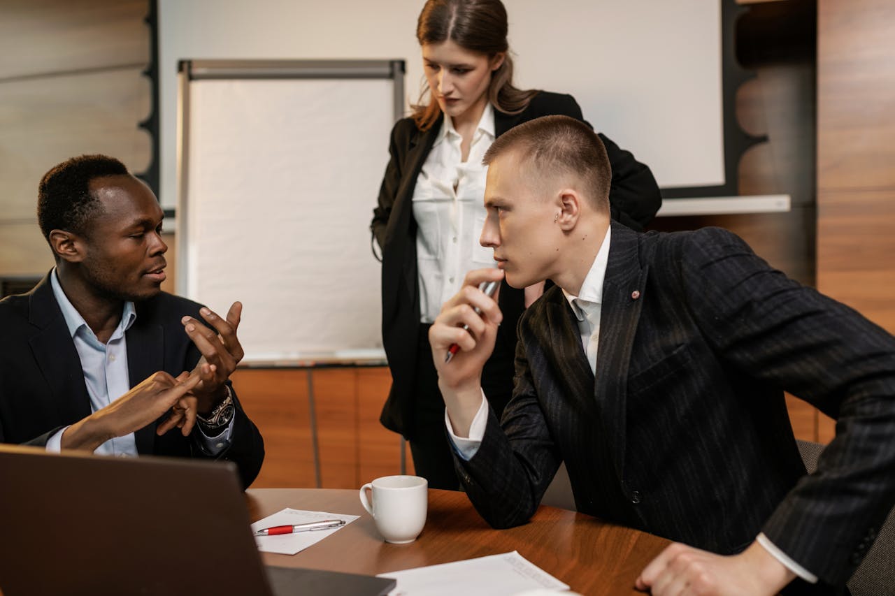 Services Diverse colleagues in active discussion around a conference table in a modern office setting.