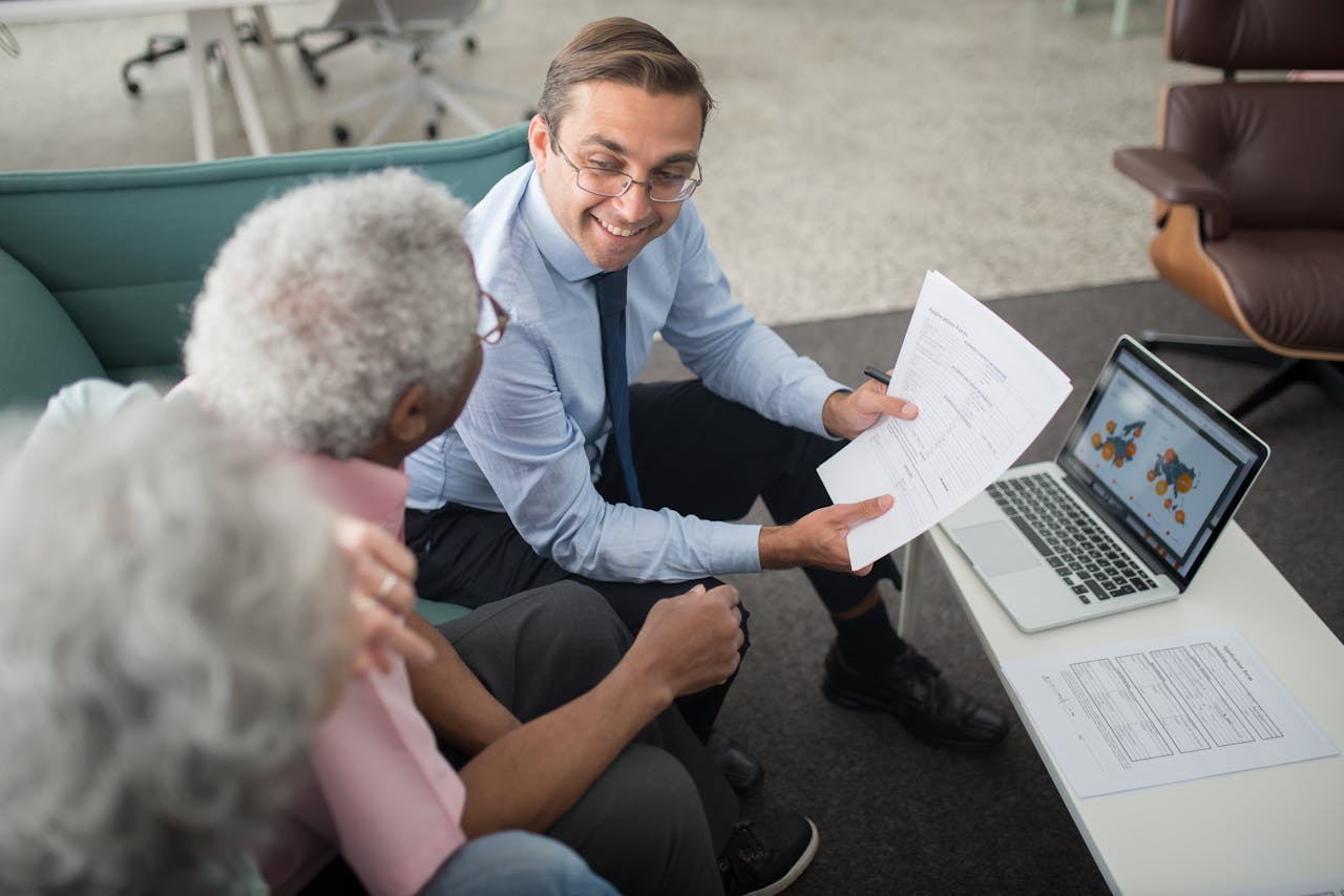 Home Financial advisor discussing documents with senior clients in an office setting, showcasing a collaborative consulting session.
